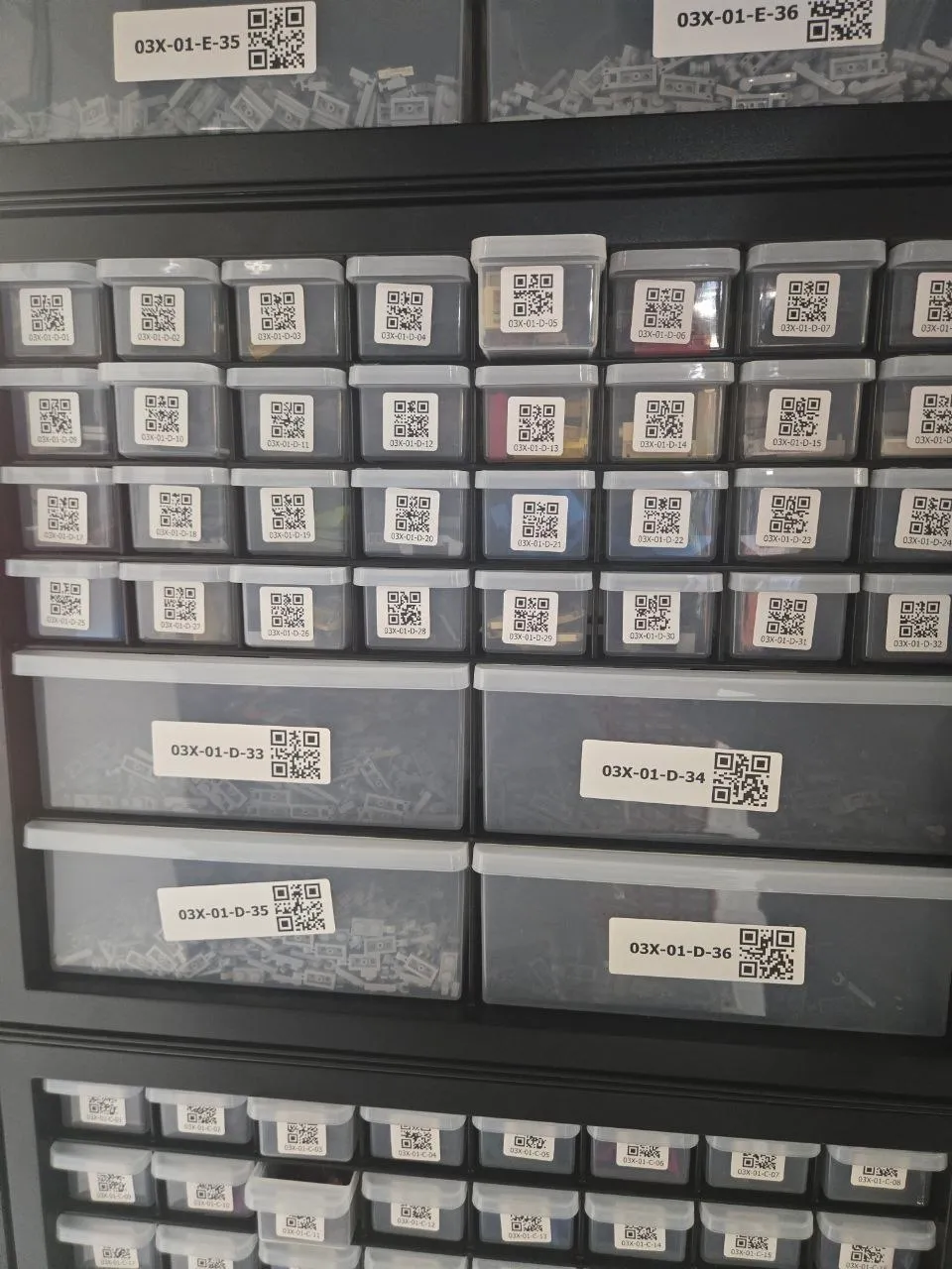 Black 36-drawer cabinet of LEGO parts with 32 small and 4 large drawers, each carrying a QR-code label