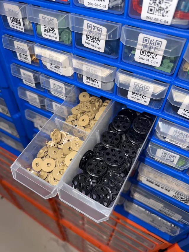 Blue VEVOR drawer pulled out, split between tan round LEGO tiles and black Technic pulleys, among QR-labeled drawers