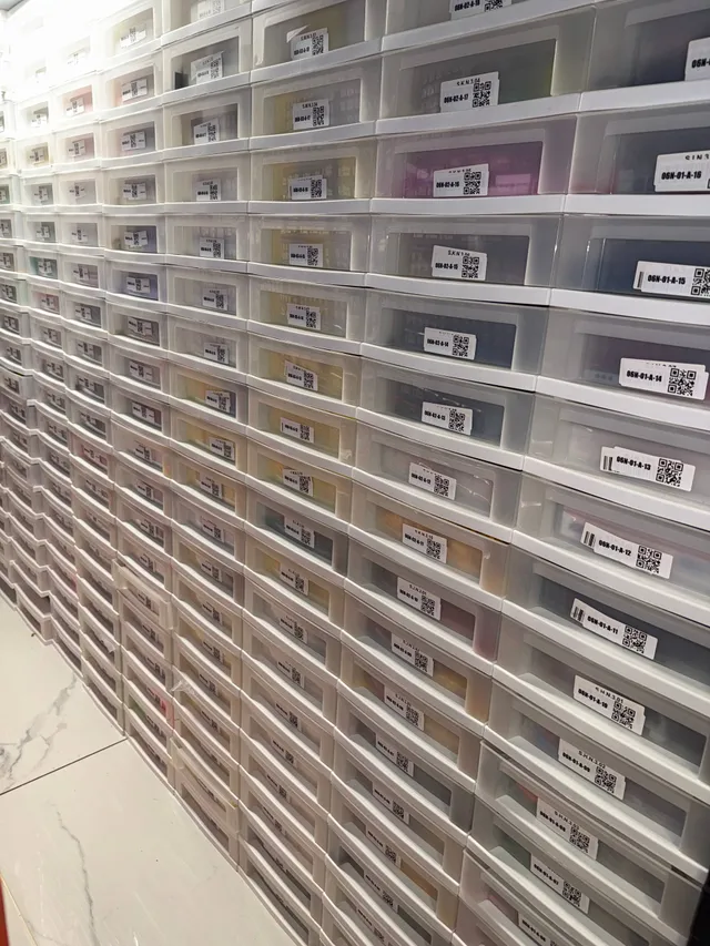 Wall of stacked white IRIS drawers of LEGO parts, each drawer front with a location code and QR label