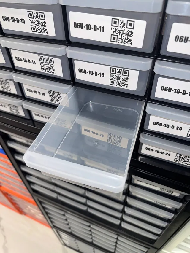 Empty drawer pulled from a black IRIS 24-drawer cabinet, showing its depth, between bold QR-code location labels