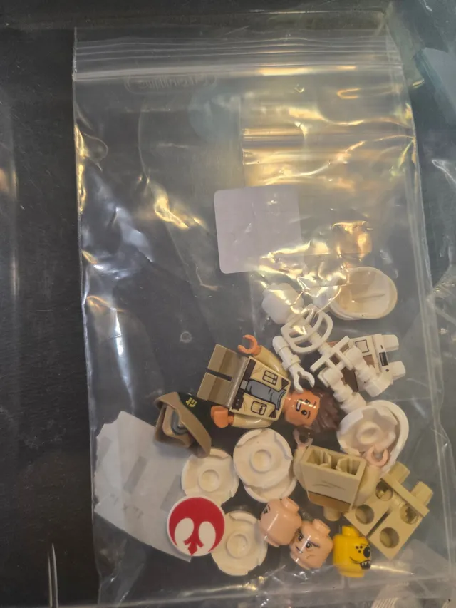 Small zip-top bag of minifigure parts, including heads, a Rebel Alliance logo tile and white droid pieces